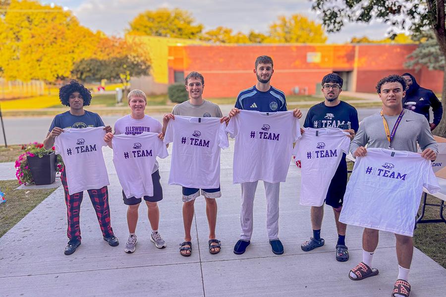 Students holding t-shirts during a volleyball tailgate.