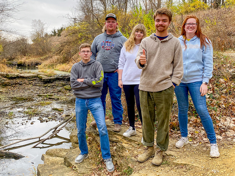 Students outside near stream of water, during activity night of conservation club.