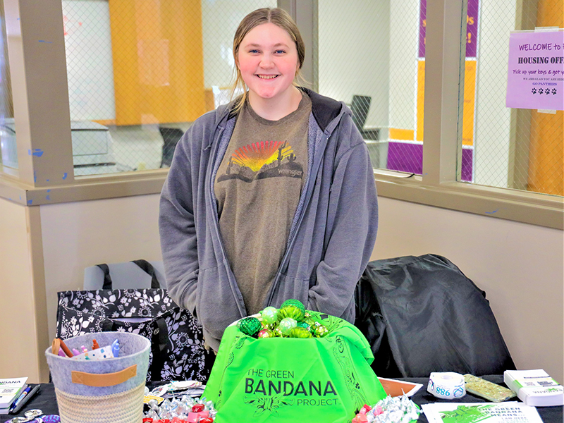 Student setup with a table with information and goodies about the Green Bandana Project. 