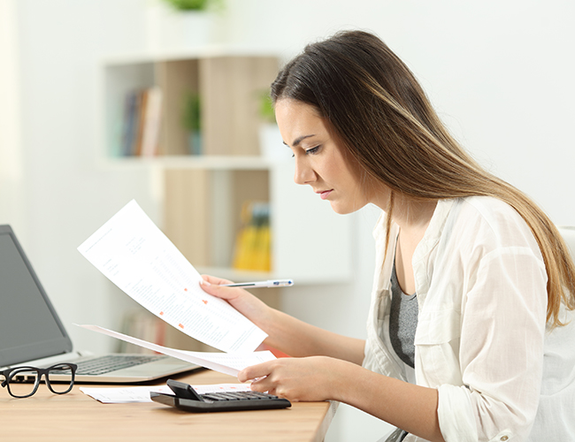 woman looking over papers and computer