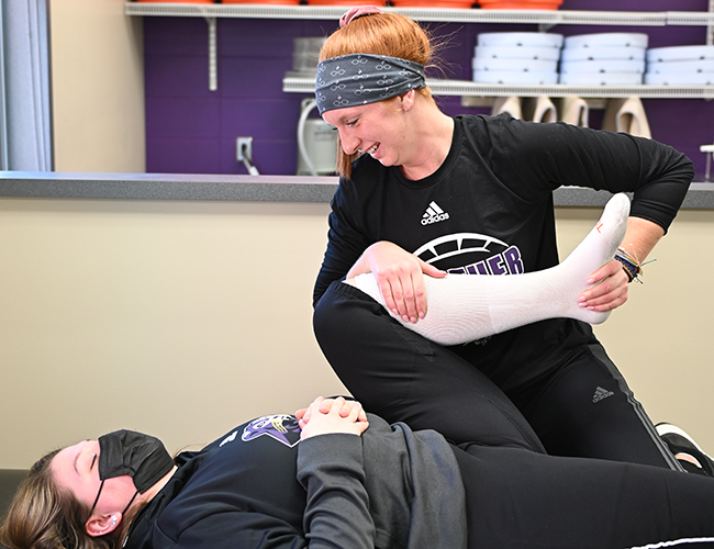 student helping another student stretch
